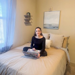 a girl sitting on a bed with a computer