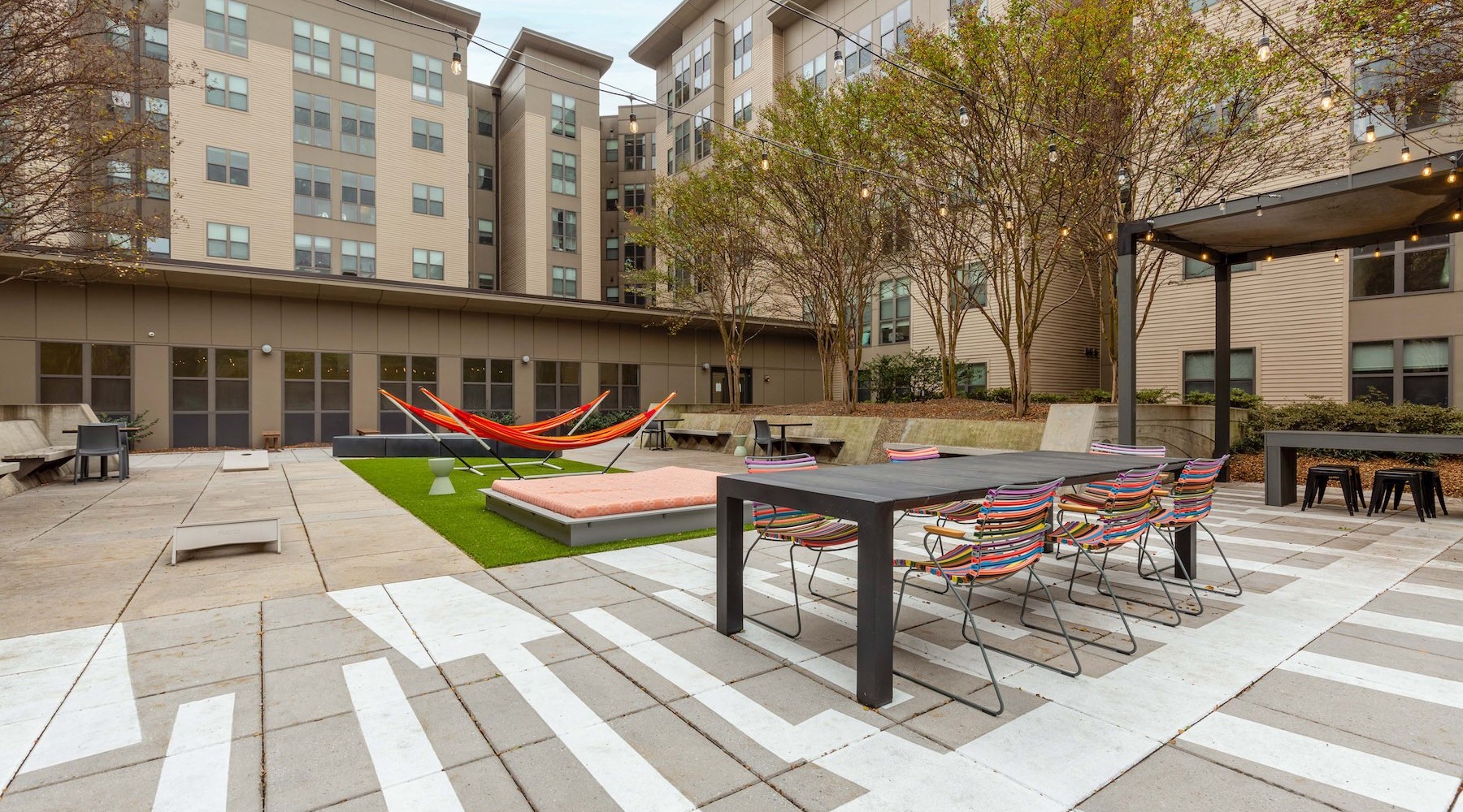a courtyard with hammocks, tables and chairs